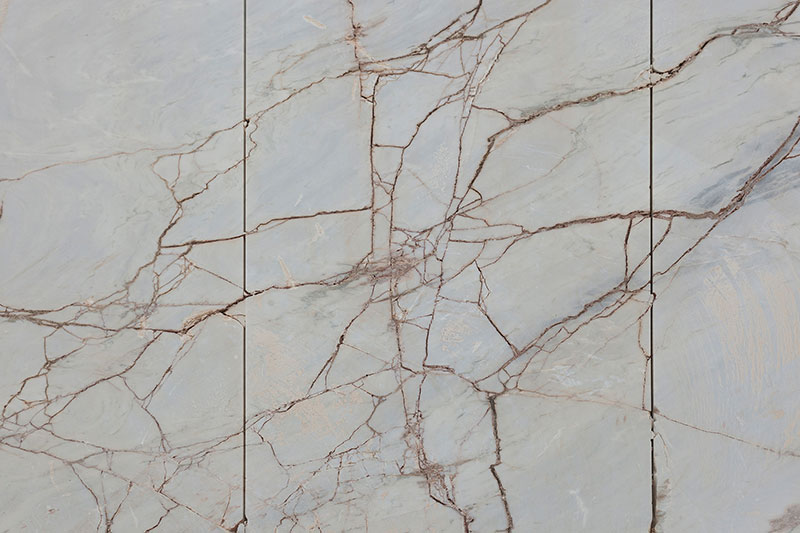 Close-up view of large polished marble slabs with intricate natural veining in warm brown and beige tones, showcasing the raw beauty of stone material used by OnEntropy.
