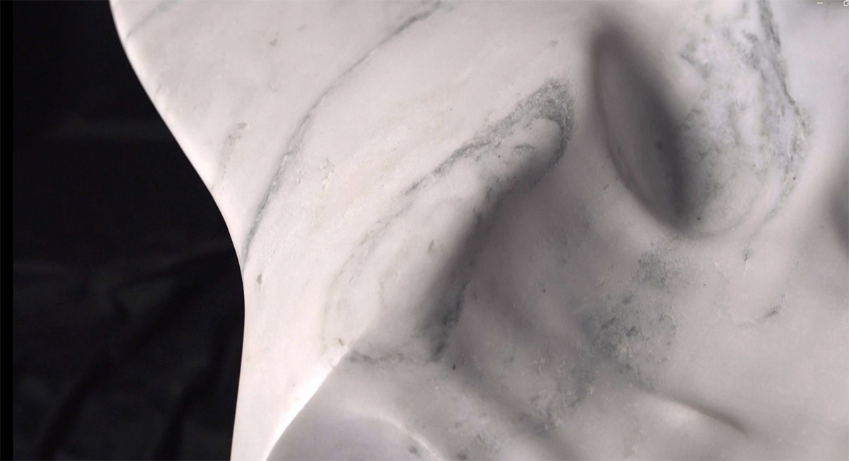 Detail view of sculpted white marble surface by OnEntropy, highlighting soft curves and natural veining that emphasize the stone's fluid, organic character.