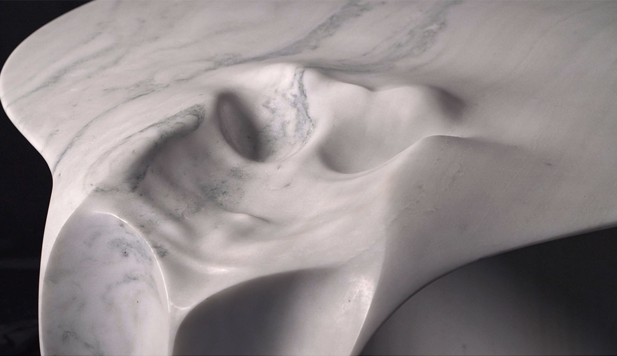 Close-up of sculpted white marble table by OnEntropy featuring fluid, draped stone folds and organic surface textures.